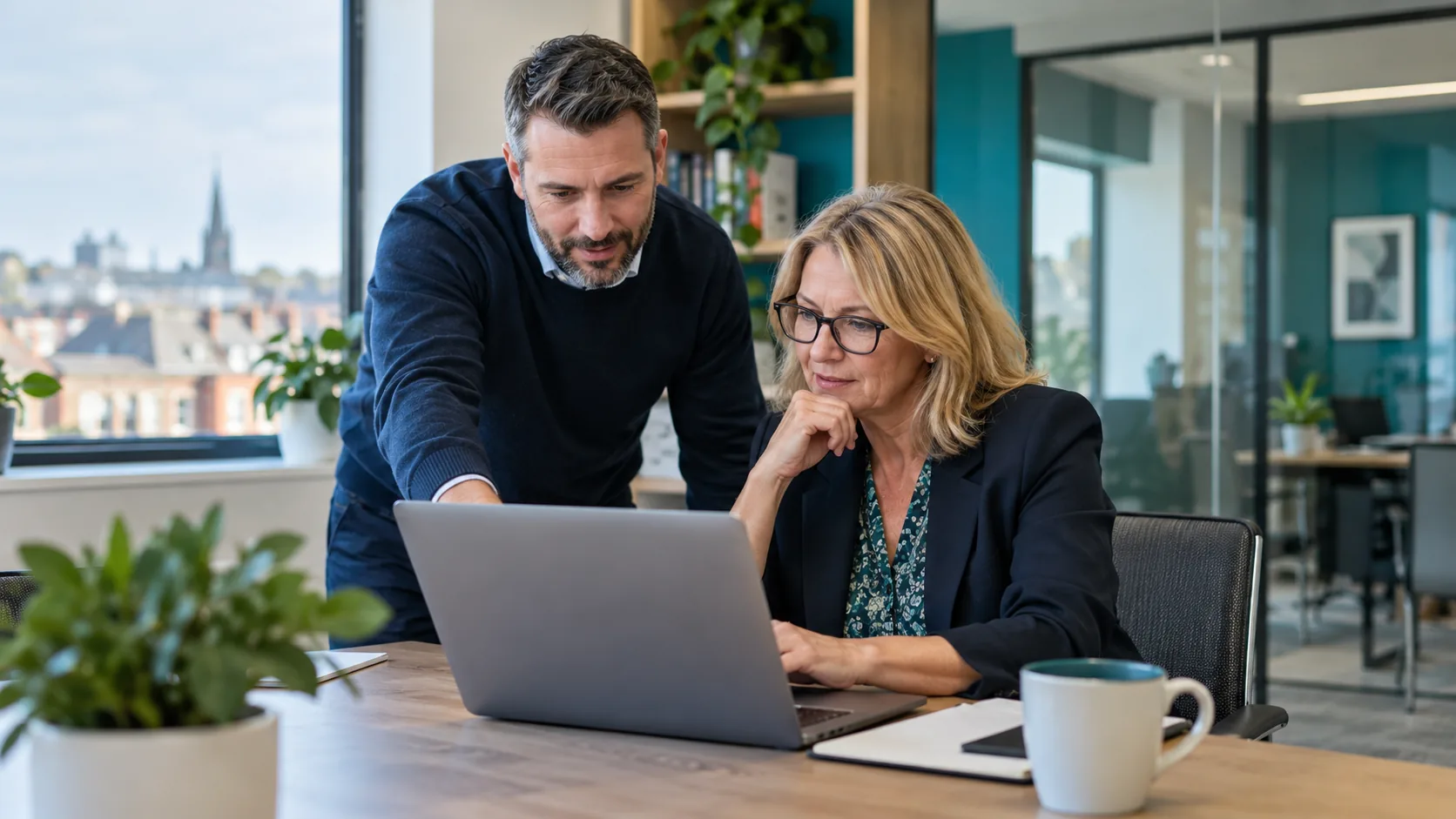 IT consultant helping a business owner use a laptop in an office