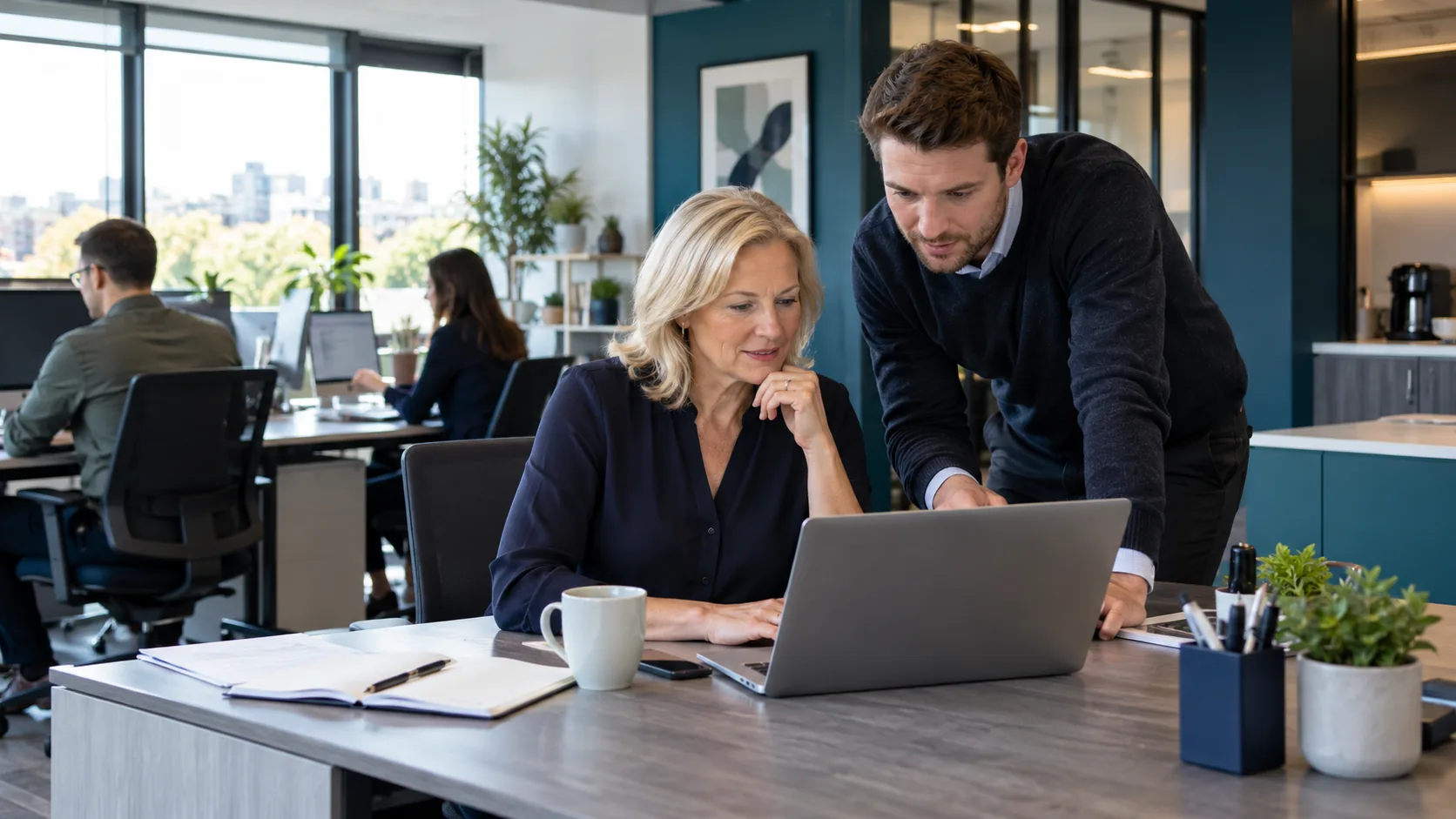 IT consultant helping a business owner use a laptop in an office