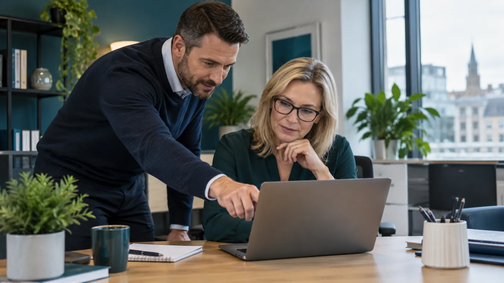 IT consultant helping a business owner use a laptop in an office