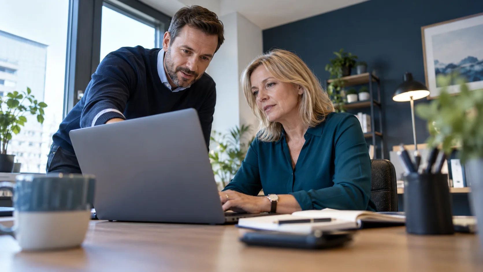 IT consultant helping a business owner use a laptop in an office