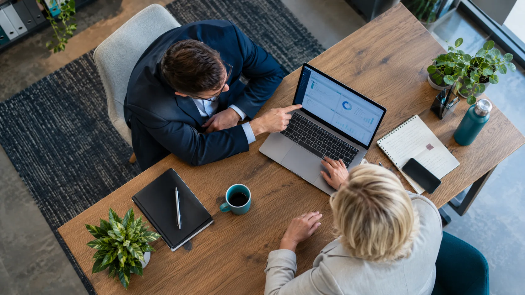 IT consultant helping a business owner use a laptop in an office